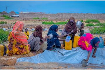 Des femmes déplacées par les conflits et les conséquences des changements climatiques en Somalie puisent de l'eau insalubre
